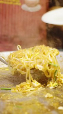 Dikey video. Angle Slow Motion Chef Büyük Pan 'dan Sokak Gıda Konseptine Pad Thai servis ediyor.