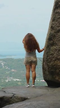 Dikey video. Genç Kadın Okyanus manzarasına bakan dev kayalara karşı duruyor Samui 'de, Doğa Keşfi