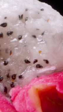 Dikey video. Siyah Tohumlu Beyaz Ejder Meyvesinin Kapanışı Parlak Işıkta Ellerle Açılıyor, Egzotik Tropikal Meyve Konsepti