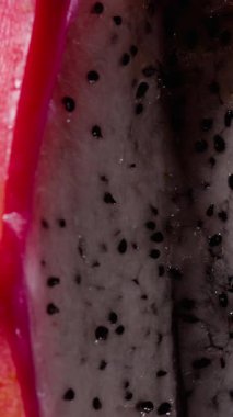 Dikey video. Siyah tohumlu Pembe Ejder Meyvesi 'nin Beyaz Etini Kapat Karanlık Arkaplan, Egzotik Tropikal Üretim Konseptine Karşı Yavaşça Döndür