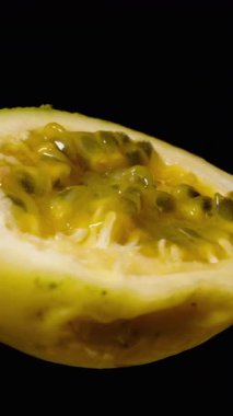 Dikey video. Yarı Kesim Sarı Tutku Çemberde Dönüyor Sulu Sarı Pulp ve Siyah Tohumları Koyu Arkaplan Karşısında Gösteriyor, Taze Egzotik Meyve Kavramı