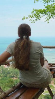 Dikey video. Geniş Okyanus ve Ada Bakışları Yüksek Açı, Rahatlama ve Meditasyon Konseptinden Tahta Platformda Oturan Kadın