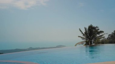 Sonsuzluk Havuzu Mavi Gök ve Palmiye Ağaçlarını Yansıtıyor Okyanus manzaralı ve Arka planda Dağlar, Lüks Seyahat Konsepti