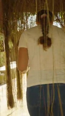 Dikey video. Parlak Güneş Işığında, Doğa Yürüyüşü Konseptinde, Tropikal Gölgede İlerlerken Köklerini Tutan Kadın