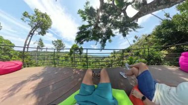 Erkek ve Kadın Bacakları Ağaç Güvertesinden Orman manzarasına bakarken Fasulye Torbalarına Dinleniyor İlk Kişi Görünümü, Rahatlatıcı Geri Çekilme Konsepti