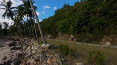 Tropikal Yol Boyunca Yürüyen Kadın Cliar Cliffside ve Okyanus Kıyısında FPV Drone Arkasında Kıyı Macerası Konseptiyle