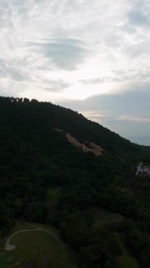 Dikey video. Günbatımında Bulutlu Gökyüzü, Tropikal Dağ ve Kıyı Çizgisi Konsepti Yüksek Drone Manzarası