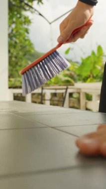 Dikey video. Açık Hava Gününde Siyah Masa Üstü Mavi Tüylü Parlak Sprey Şişe ve Pencere Yanındaki Kişi