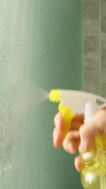 Dikey video. Tiled Banyodaki Islak Cam Yüzey Üzerine El Spreyi Temizleme Çözümü