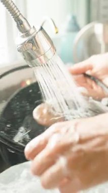 Dikey video. Ellerin Yakın Çekimi Ot Yıkama Odunu, Musluk Suyunun Altında Ahşap Tutamakla Kapalı Pencere