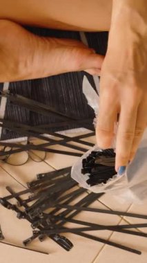 Dikey video. Yere uzanan siyah kablo bağlarının içine uzanan eller, ekipman düzenleme kavramı