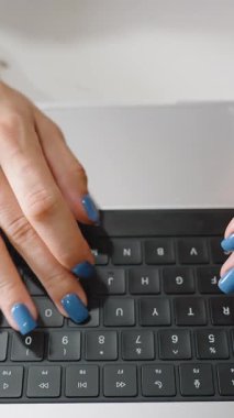 Dikey video. Mavi Çivi Cilalı Kadın Ellerinin Kapanışı Klavye Klavyesinde Yukarıdan Yazıyor