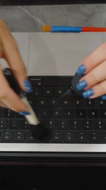 Dikey video. Kadın Laptop Temizleme Klavyesi Tepeden Görünen Masadaki Temizleme Aletleri ile Fırça ve Hava Fırçası Kullanıyor