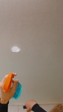 Dikey video. Cam Panele Temizleyici köpük püskürten ve Siyah Sünger Tutan Kişi Genel Görünümü