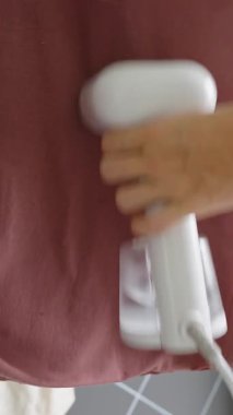 Dikey video. Maroon T-Shirt 'ün El Buharı, Detay Açısı, Çamaşır Bakımı Konsepti