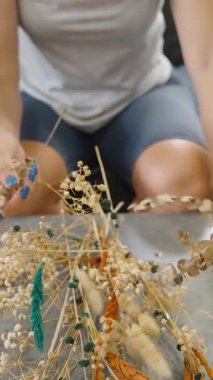 Dikey video. Masaya Kuru Çiçekler Düzenleyen Kadın Kahverengi Vazo, Geniş Açı, Ev Dekorasyonu Konsepti