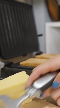 Dikey video. Sandviç için kızarmış ekmeğin üzerine peynir dilimleri yerleştiren eller, yakın çekim açısı, Fast Food kavramı.