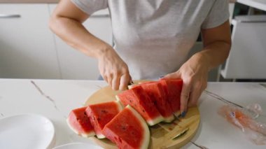 Yuvarlak kesim tahtasında karpuz dilimleyen kadın, yakın çekim açısı, sağlıklı beslenme kavramı.