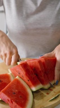 Dikey video. Yuvarlak kesim tahtasında karpuz dilimleyen kadın, yakın çekim açısı, sağlıklı beslenme kavramı.