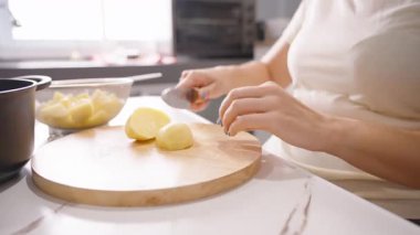 Kadın Soyulmuş Patatesleri Tahta Kesme Tahtasına Dilimliyor. Yanında Cam Kase, yan açı, Ev Yemeği Konsepti.