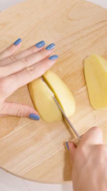 Dikey video. Yakınlarda Süzgeç ve Ot Otu Konseptiyle Patates Kesen Kadın Yuvarlak Tahta Kurulunda Genel Görünüm, Ev Pişirme Konsepti