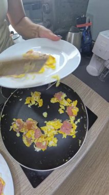 Dikey video. Yumurta ve jambon servis eden kadın Pan on Soba 'dan Beyaz Tabağa, Balıkgöz Perspektifi Mutfak Düzenlemesi, Hızlı Kahvaltı Konsepti