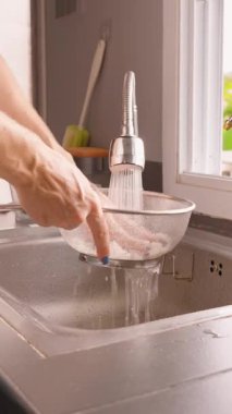 Dikey video. Kadın Pirinç Yıkama Süzgeci Altında Musluk Akımı, Yan Açı, Sağlıklı Aşçılık Konsepti