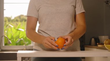 Mutfak Tezgahı, Orta Açı, Sağlıklı Atıştırma Konsepti 'nde Elle Taze Portakal soyan Kadın