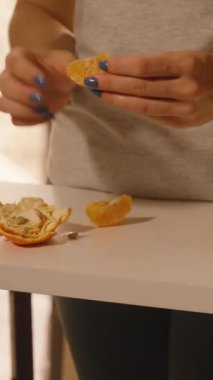 Dikey video. Parlak Mutfak, Orta Açı, Sağlıklı Atıştırmalık Konsepti 'nde Elinde Portakal Dilimleyen Kadın