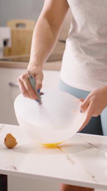 Dikey video. Mutfak Masasında Un, Orta Açı, Hamur Hazırlama Konsepti 'nin yanında Beyaz Kasede Yumurta Karıştırma Kadın