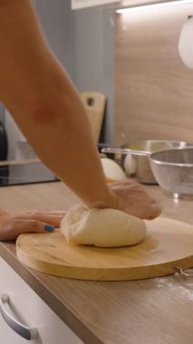 Dikey video. Modern Kitchen 'da Tahta Yuvarlak Yuvarlak Masa' da Knewing Hamur 'u Yan Görünümlü Kadın, Ev Yapımı Pişirme Konsepti