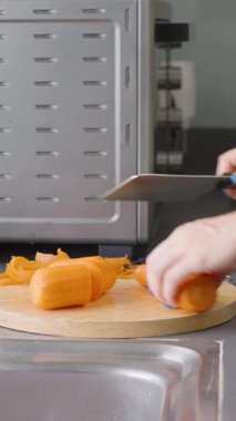 Dikey video. Mutfak 'ta Havuç soyan Kadın Sebze Soyucu Kesme Kurulu Sağlıklı Yemek Hazırlama