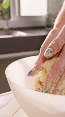 Dikey video. Eller Mutfak Tezgahındaki Beyaz Kasede Parlak Hamur 'u Pencere' den Güneş Işığıyla Karıştırıyor, Açıyı Kapat, Yavaş Hareket, Ev Yapımı Pişirme Konsepti