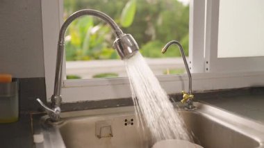 Mutfak musluğundan Paslanmaz Çelik Lavabo 'ya akan Akan Su Kişi Yaklaşıyor ve Kapanıyor, Açıyı Kapat, Yavaş Hareket, Ev Hali Ulaşımı