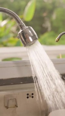 Dikey video. Mutfak musluğundan Paslanmaz Çelik Lavabo 'ya akan Akan Su Kişi Yaklaşıyor ve Kapanıyor, Açıyı Kapat, Yavaş Hareket, Ev Hali Ulaşımı