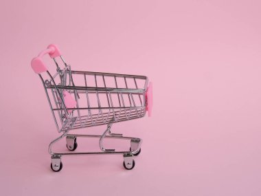 Pembe arka planda küçük boş market arabası