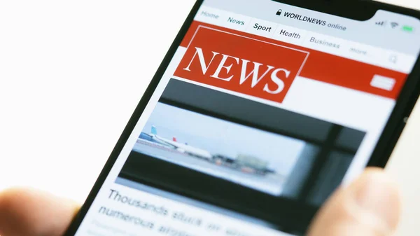 Online news on a smart phone. Businessman reading news or article on a mobile phone screen app. Hand holding smart device. Newspaper and portal on internet. Displayed news are not reality related.