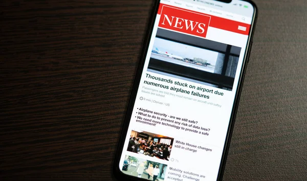 Online news on a smart phone. Businessman reading news or article on a mobile phone screen app. Hand holding smart device. Newspaper and portal on internet. Displayed news are not reality related.