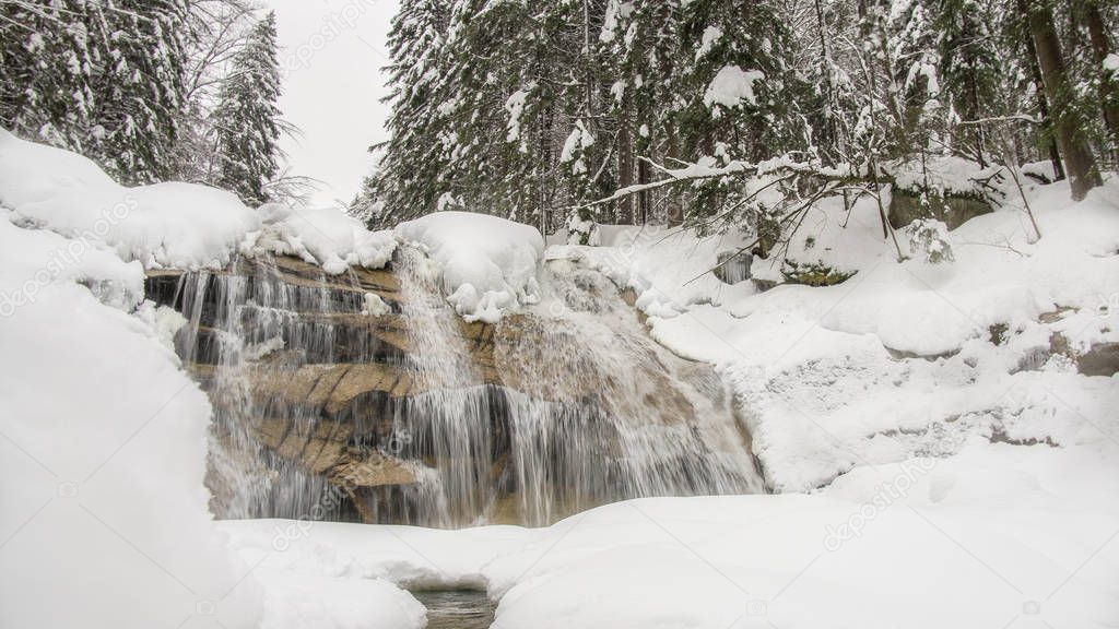 Waterfall in the forest at the river, winter landscape in winter with snow, Harrachov Czech Republic Harrachov