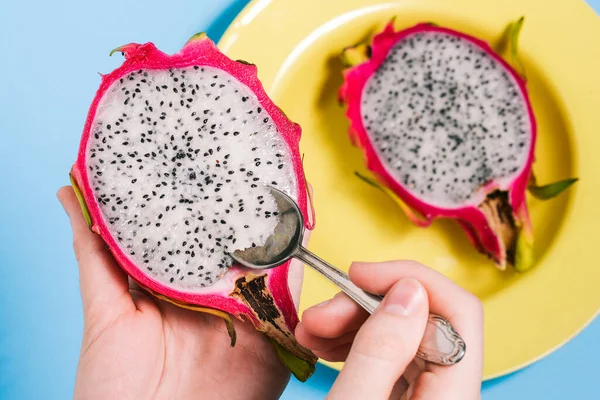 Bir kadın kaşıkla taze pitaya yiyor. Pitaya 'yı bir adamın ellerinde yakın plan kes. Sağlıklı beslenme. Vejetaryen yemeği.