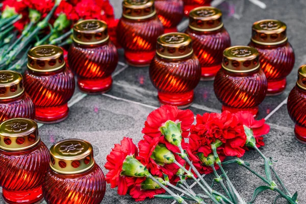 Red carnations on a marble slab and funeral lamps. Symbol of mourning, laying flowers at the memorial