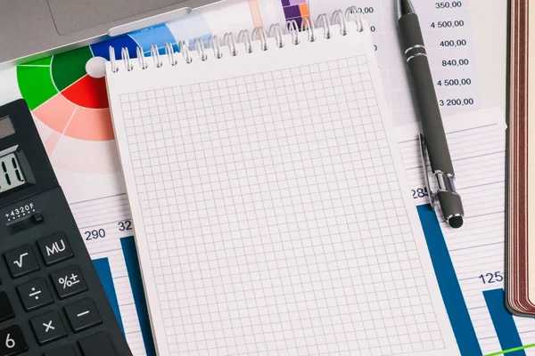 Boş Notepad sayfası, bir hesap makinesi, bir kalem ve üzerinde numaralar olan finansal kağıtlar. Ticaret, yatırım ve bankacılık