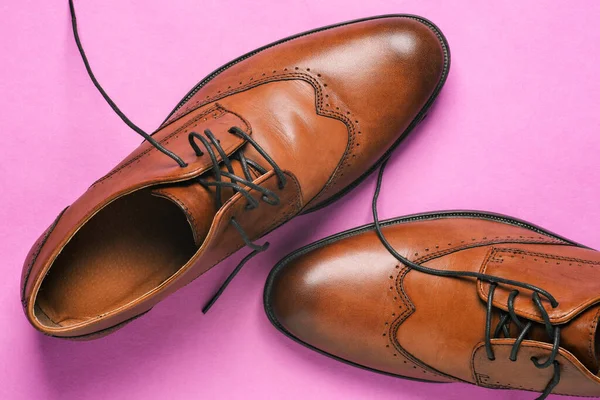 Brown men\'s shoes close-up. Classic shoes with untied laces on a pink background. Shoes for weddings, everyday walking and office shoes. Men\'s style.