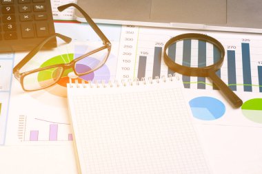 Finansal belgeler, çizelge, büyüteç, hesap makinesi, dizüstü bilgisayar ve gözlük. Metin için boş Not Defteri sayfası. Görüntü oluşturuldu. İş konsepti