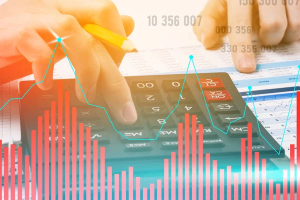 Businessman counts on a calculator. Earnings growth chart and figures. Company revenue forecast and data analysis. Business concept. Tinted photo.