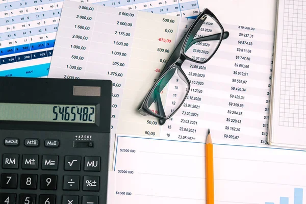 Finansal belgelerde gözlük, hesap makinesi ve kalem var. Analitik rapor ve pazarlama araştırması. Şirket raporlarıyla grafikler. İş konsepti.