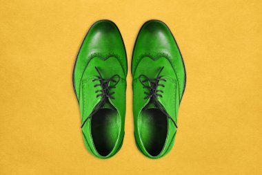 Sarı arka planda hakiki deriden yapılmış yeşil erkek ayakkabıları. Asgari yaratıcı biçim.