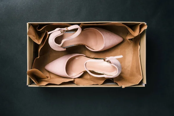 Béžové boty v obdélníkové krabici na černém pozadí. Nové dámské boty se zapínáním v obalu. Dámská móda. Horní pohled na ploché rozložení. — Stock fotografie