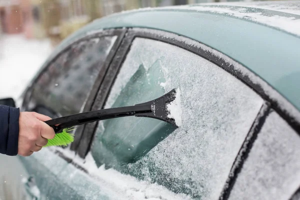 brushing the car off the snow with brush