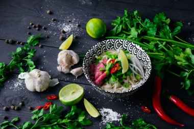 Pho Bo Vietnamca çorbası erişte, sığır eti, chili biber, soğan, kişniş ve limon koyu siyah arka plan üzerine